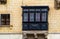 Traditional Maltese wooden balcony painted in black with lace curtains