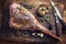 Traditional marinated barbecue aged leg of venison with mushrooms and herbs on a rustic wooden board