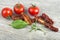 Traditional mediterranean kitchen - delicious dried tomatoes with fresh tomatoes, rosemary branch and basil leaf on wooden desk