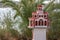 Traditional and memorial roadside small chapel or church in Greece with palm tree and sea in background