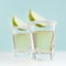 Traditional mexican golden tequila alcohol drink with lime and salt edge in shot glass on elegant blue color background, square.
