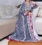 Traditional Moroccan dress. A model wearing a Moroccan caftan sits on a sofa