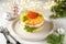 Traditional New Year`s Russian salad `Mimosa` with canned fish, potatoes, cheese, carrots and eggs. Christmas light background.