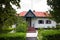 Traditional old wooden house with tin roof, little orchard in yard and cherry tree with ripe berries