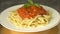 Traditional pasta bolognese served on a white plate and garnished with basil Close up