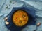 Traditional pea soup with meat, carrots, paprika, jalapenos and turmeric. Soup on a blue linen tablecloth, next to garlic cloves,