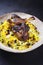 Traditional Persian tahdig jeweled javaher polow bride basmati rice with slow cooked lamb shank on a rustic design plate