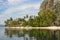 Traditional philippinian boat near idyllic beach with palm trees and mountain. Tropical landscape of Ellis island in Philippines.