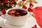 Traditional Polish christmas soup - red borscht soup with dumplings on white plate.