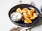 Traditional Polish dish - pierogi or dumplings or vareniki potatoes and mushrooms with sour cream and fried onions in black plate
