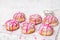 Traditional Polish donuts with pink frosting and heart sprinkles on light background.