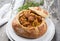 Traditional Polish kraut stew bigos with sausage and meat filled in white bread on a plate