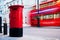 Traditional red mail letter box and red bus in motion in London, the UK.