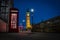 Traditional red phone booth or telephone box at night with Big Ben in the background, the famous english landmark in London,