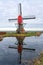 Traditional red wip windmill reflected in water, Holland landscape