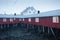 Traditional red wooden houses on the shore of Reine fjord. Beautiful winter scene of Vestvagoy island. Picturesque morning view