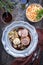 Traditional rolled boar roast with bread dumpling, fried chicory and mushroom on a pewter plate with game red wine sau