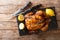 Traditional rotisserie chicken served with lemon closeup on a slate board on a table. Horizontal top view