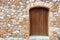 Traditional rural home facade background. Stonewall cottage exterior with wooden brown door. Greece