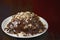 Traditional Russian anthill cake with chocolate and nuts on a black wooden background.