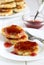Traditional russian cottage cheese pancakes with sweet berry sauce on a white table.