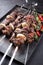 Traditional Russian lamb shashlik on a barbecue skewer with chili, onion and sumach on a rustic metal tray