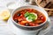 Traditional Russian meat soup Solyanka in bowl on rustic wooden table