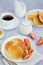 Traditional Russian pancakes on kefir with honey, sour cream, fresh strawberries and kiwi on a white plate with a cup of coffee.