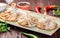 Traditional russian pelmeni, ravioli, dumplings with meat in plate on wooden background. Parsley, sour cream and spices