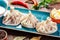 Traditional russian pelmeni, ravioli, dumplings with meat in plate on wooden background. Parsley, sour cream and spices