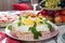 Traditional Russian salad herring under a fur coat on a large white dish decorated with greens and eggs with red caviar