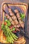 Traditional Russian shashlik on a barbecue skewer with green asparagus and paprika on a burnt wooden cutting board