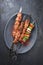 Traditional Russian shashlik on a barbecue skewer with vegetable and onion on a modern design cast iron plate