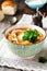 Traditional Russian soup-Rassolnik with pickled cucumber, barley, chicken, tomatoes and parsley in ceramic bowl. Selective focus