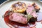 Traditional saddle of venison with Swiss roesti, quince and orange slices in game red wine sauce on a modern design plate