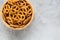 Traditional salty mini pretzels in wooden bowl on a gray backround