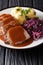 Traditional Sauerbraten dish with potato dumplings and red cabbage close-up. German cuisine. vertical