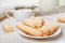 Traditional savoiardi biscuits or ladyfingers cookies on a white plate and a white cup of coffee
