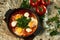 Traditional shakshuka with eggs, tomatoes and parsley in a frying pan