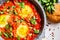 Traditional shakshuka in  pan. Fried eggs in tomato sauce with herbs, top view