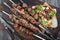 Traditional shashlik skewer with salad and yufka bread on an old burnt wooden cutting board