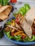 Traditional Shawarma Delight: Savory Chicken, Fries, and Fresh Veggies Wrapped in Pita - Rustic Brown Wall Setting. AI Generated