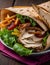 Traditional Shawarma Delight: Savory Chicken, Fries, and Fresh Veggies Wrapped in Pita - Rustic Brown Wall Setting. AI Generated