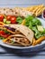 Traditional Shawarma Delight: Savory Chicken, Fries, and Fresh Veggies Wrapped in Pita - Rustic Brown Wall Setting. AI Generated