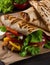 Traditional Shawarma Delight: Savory Chicken, Fries, and Fresh Veggies Wrapped in Pita - Rustic Brown Wall Setting. AI Generated