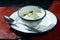Traditional Slavic Okroshka soup with radishes, herbs, turkey and white yogurt in a metal bowl on a dark background. Restaurant