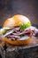 Traditional sliced cold cuts roast beef sandwich with onion, gherkin and remoulade on an old wooden board with