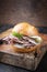 Traditional sliced cold cuts roast beef sandwich with onion, gherkin and remoulade on an old wooden board