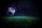 Traditional soccer ball on soccer field. Close up view of soccer ball (football) on green grass with dark toned foggy background.