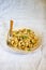 traditional soviet russian pasta dish, vermicelli, navy pasta, with meat on a white plate on a light fabric background. Minimalism